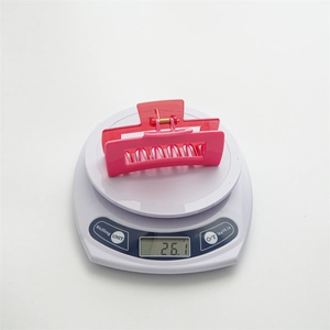 Détail d'une pince à cheveux rectangulaire rose vif pesant 26,1 g sur une balance