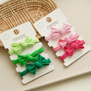 Detail view of colorful bow hair ties on card display featuring soft knitted elastic bands