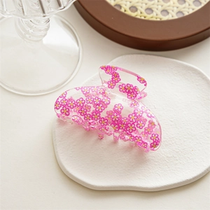 Detail of a transparent acrylic hair claw clip with yellow and pink floral daisy patterns