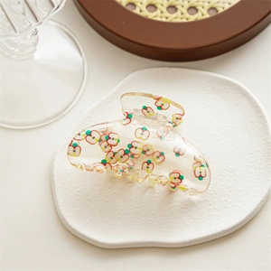 Close-up of transparent acrylic hair claw clip with cute red apple pattern design
