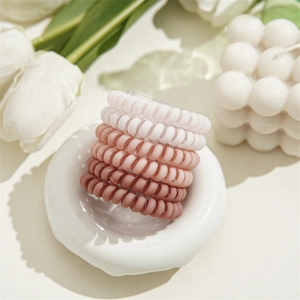 Détail de chouchous spirales dégradés roses sur un plateau avec tulipes blanches
