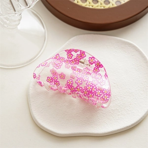 Detail of transparent pink floral acrylic hair claw clip on a decorative tray