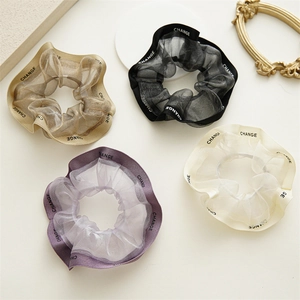 Détail de quatre chouchous en organza dorés, noirs, violets et blancs avec rubans Change