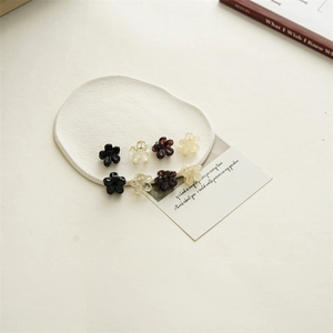 Detailed view of eight mini 2cm flower hair claws in cream, black, and amber resin tones