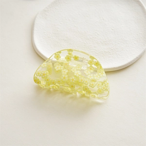 Detail view of transparent acrylic hair claw with yellow and white floral patterns