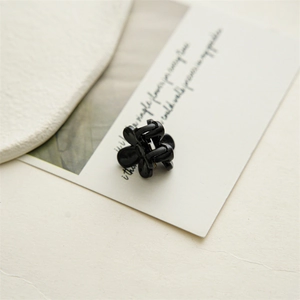 Detailed close-up of a 2cm mini black flower hair claw clip with glossy resin finish