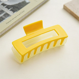 Vue macro d'une grande pince à cheveux rectangulaire jaune vif sur un plan lisse