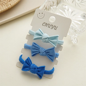 Detailed view of three blue bow hair ties on a white display card with elastic texture