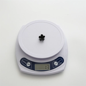 Mini 2cm black flower hair claw clip displayed on a digital scale for precise weight