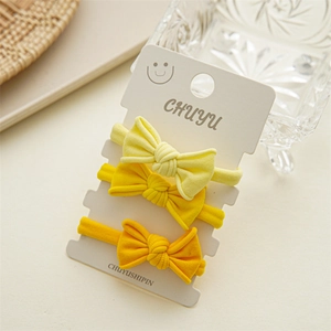 Detailed view of three yellow bow hair ties on a display card with a soft knit texture