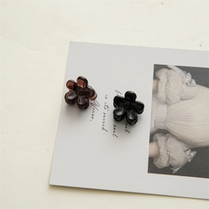 Close-up of 2cm mini flower hair claws in translucent brown and black resin finish