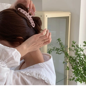 Pince à cheveux rose en forme de chaîne portée sur cheveux bruns pour un look élégant