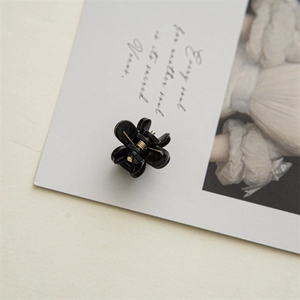 Detailed macro view of 2cm black flower hair claw with durable gold metal spring