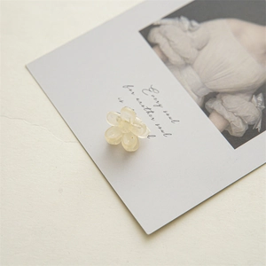 Detail view of a 2cm mini cream yellow flower hair claw made of translucent acrylic