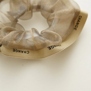 Détail du chouchou en organza champagne avec ruban imprimé de lettres CHANGE