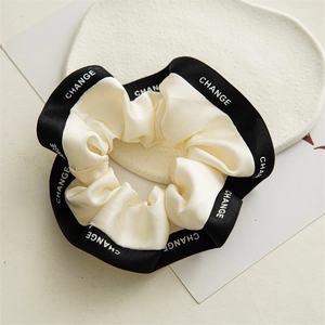 Vue détaillée du chouchou crème avec bordure noire et lettrage CHANGE blanc élégant