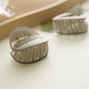 Makro-Detail einer kleinen, durchsichtigen rauchgrauen Acryl-Haarklammer für Damen-Styling