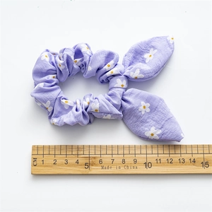 Purple floral scrunchie with bunny ear bow and measurement ruler on white background