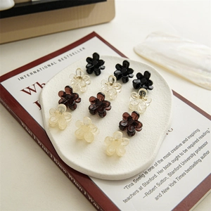 Set of 12 mini flower hair claws in multiple colors arranged on a white decorative plate
