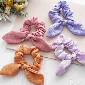 Close-up of four colorful daisy print scrunchies with bunny ears on a soft background