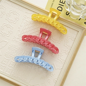 Détail de pinces à cheveux aux couleurs bonbon jaune, rose et bleu avec motif chaîne