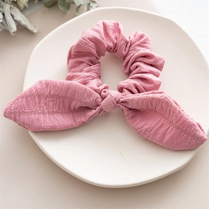 Close-up of pink scrunchie with rabbit ear bow on white ceramic tray