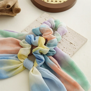 Détail d'un chouchou en mousseline arc-en-ciel avec de longs rubans et tissu soyeux