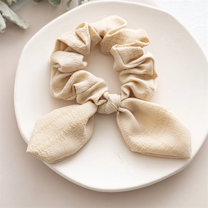 Close-up of bunny ear hair scrunchie with beige checkered fabric on ceramic plate