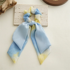Détail du chouchou en mousseline tie-dye bleu et jaune avec de longs rubans élégants