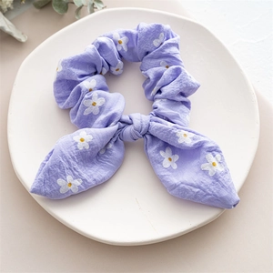 Detail of lavender scrunchie with bunny ear bow and white daisy patterns on fabric