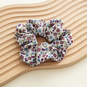 Détail d'un chouchou floral avec motifs violets et bleus sur un plateau en bois