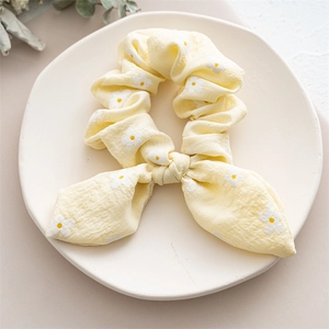 Detail of yellow daisy floral scrunchie with bow knot on a ceramic tray display