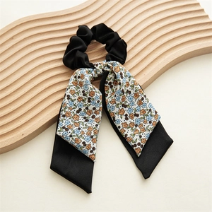 Détail d'un chouchou à ruban floral avec fleurs vintage sur satin noir lisse et brillant