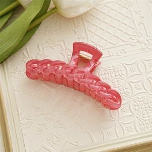 Détail d'une pince à cheveux rose en résine de couleur bonbon sur plateau décoratif
