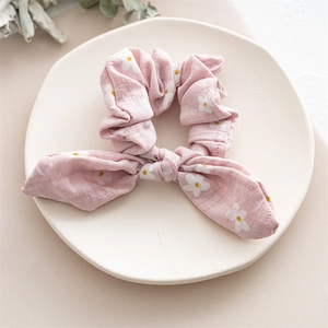 Detail of pink bow hair tie with white daisy pattern on textured linen fabric