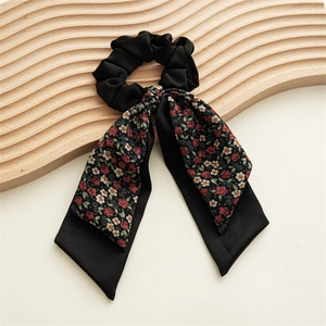 Détail d'un chouchou à nœud floral avec de longs rubans sur un support en bois
