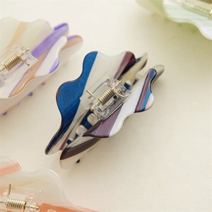 Detail shot of wavy acetate hair claw clips with colorful marble texture and metal spring