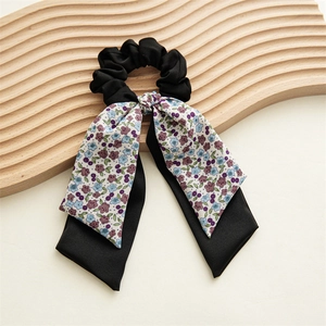 Détail d'un chouchou à motif floral avec de longs rubans sur un support en bois