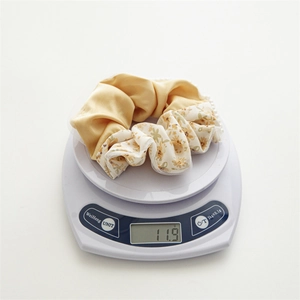 Detail view of floral scrunchie with lace edge and pearls weighing 11.9g on a scale