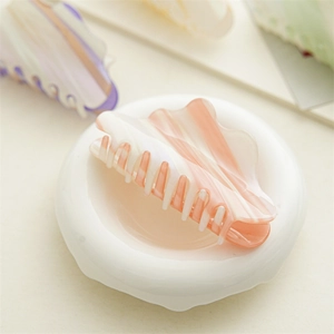 Detail view of pink and white gradient acetate hair claw clip on ceramic plate