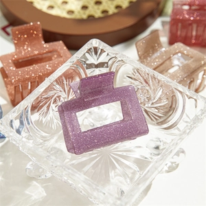 Gros plan sur une pince à cheveux à paillettes violettes au design rectangulaire