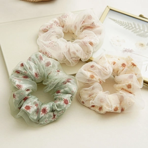 Detailed macro view of three double-layer mesh floral scrunchies in pastel colors