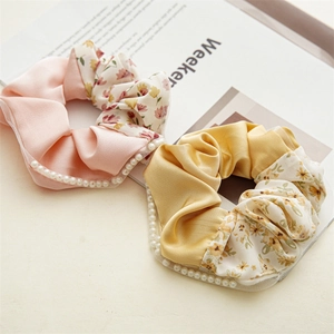 Detailed close-up of floral fabric hair scrunchies with faux pearl edges and mesh trim