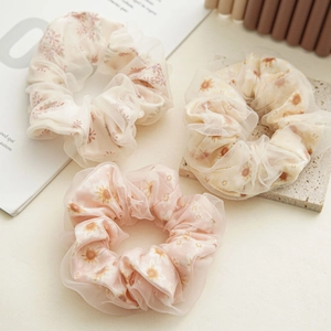 Three-piece set of mesh scrunchies with delicate daisy floral patterns in warm tones