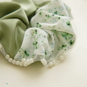 Detailed macro view of floral fabric scrunchie with satin texture and white pearl trim
