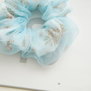 Close-up of double-layer light blue mesh scrunchie with delicate brown floral patterns