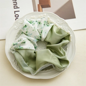 Detail of satin floral scrunchie with lace edge and white pearls in a ceramic tray