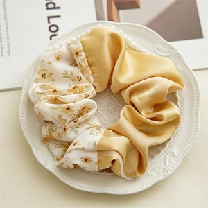 Detail of yellow floral satin scrunchie with lace trim on a decorative white ceramic plate