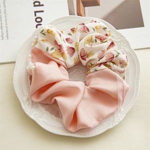 Detail of pink floral fabric scrunchie with lace and pearls on a white ceramic plate