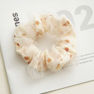 Close-up of double-layer beige mesh scrunchie with sun patterns and soft texture
